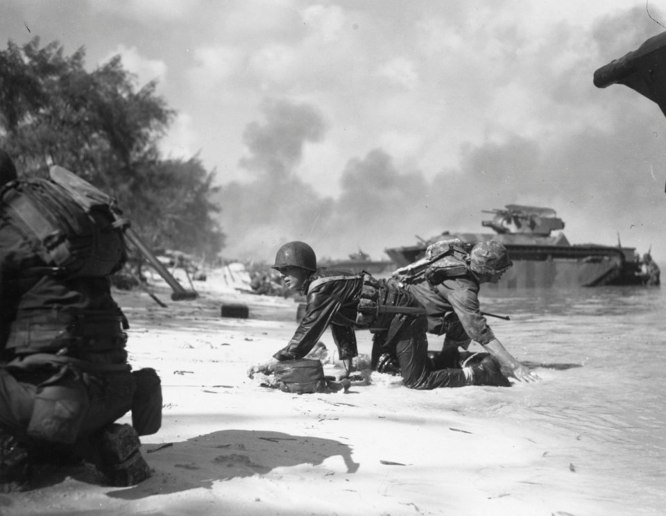 Marines crawling under fire on the beach at Saipan.