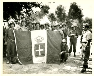 U.S. soldiers pose with a surrendered Italian flag for a C…