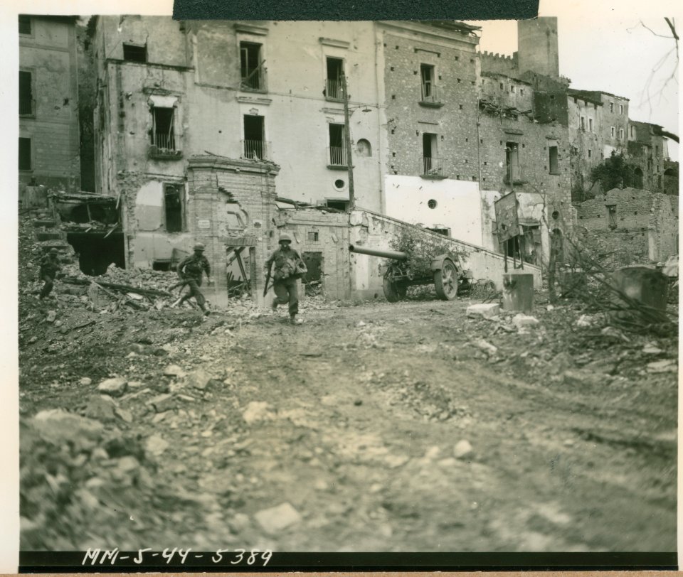 American infantrymen dash for cover across the town square…