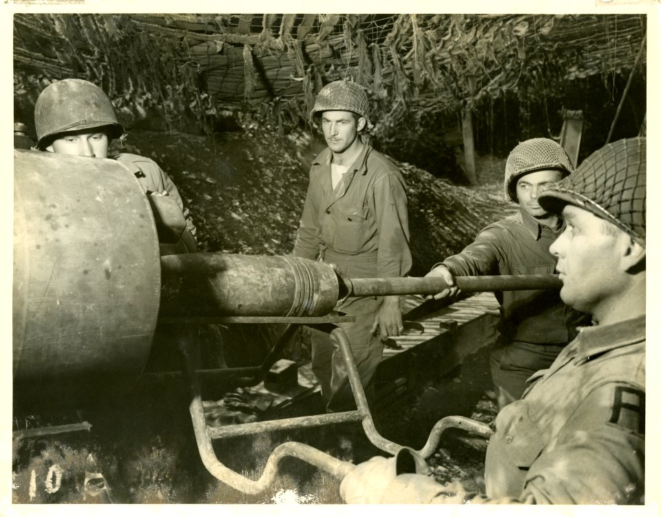 This action photo shows a gun crew loading their weapon. L…