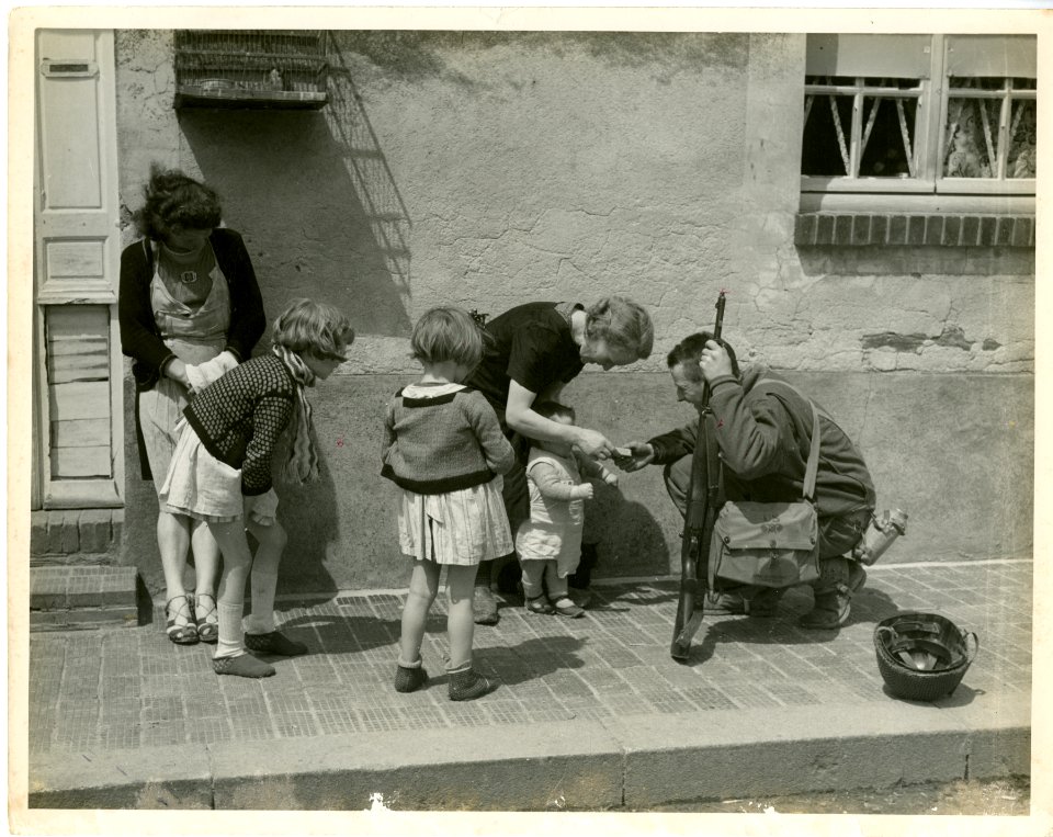 An American soldier gives candy to French children, July 1…
