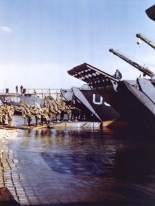Medics and litter bearers going up the ramp of an LCT whic…
