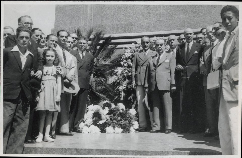 "Manuel Blasco Garzón, retrato de grupo. En reverso: Momento en que la Delegación del Gobierno Republicano Español pone la ofrenda floral en la estatua del libertador general Artigas, situada en la Plaza de la Independencia."