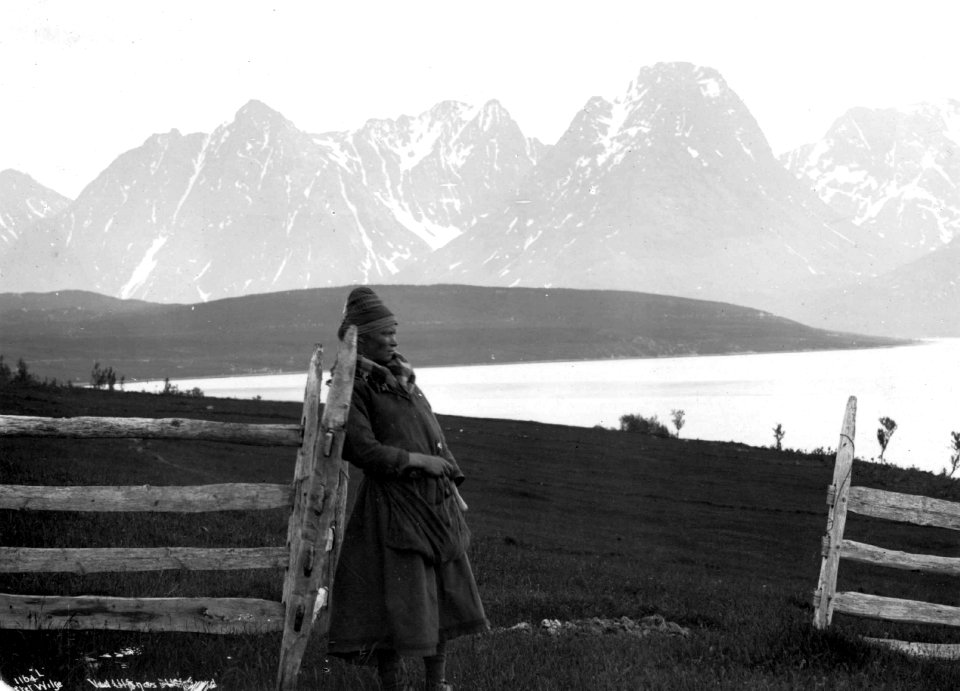 Oversiktsbilde fra Ullsnes med en svensk samejente ved et gjerde. Karlsøy 1889 - Norsk folkemuseum - NF.06789-009