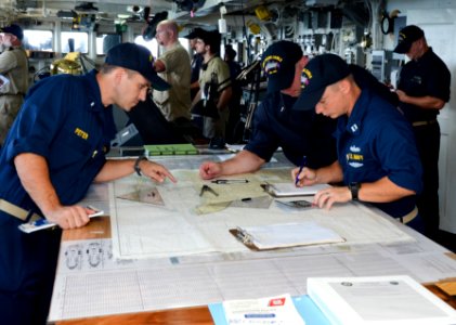 Officers aboard USS Frank Cable review sea charts while leaving port. (16007377983)