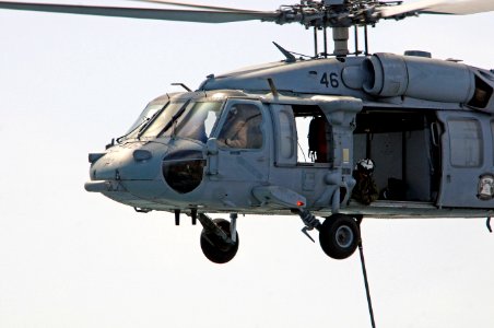 A U.S. Navy Naval Air Crewman looks out from an MH-60S Seahawk helicopter assigned to Helicopter Sea Combat Squadron (HSC) 23 carrying supplies during a vertical replenishment between fast combat support ship 110517-N-RC734-120