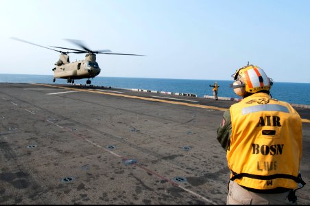 A U.S. Sailor directs an Army CH-47F Chinook helicopter assigned to the 3rd General Support Aviation Battalion, 2nd Combat Aviation Brigade, 2nd Infantry Division to land aboard the amphibious assault ship USS 140411-N-LM312-027 photo