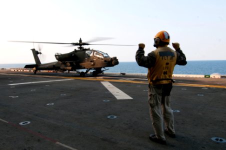 A U.S. Sailor directs the pilots of an Army AH-64D Apache Longbow helicopter assigned to the 4th Aerial Reconnaissance Battalion, 2nd Combat Aviation Brigade, 2nd Infantry Division to land aboard the amphibious 140411-N-LM312-103 photo