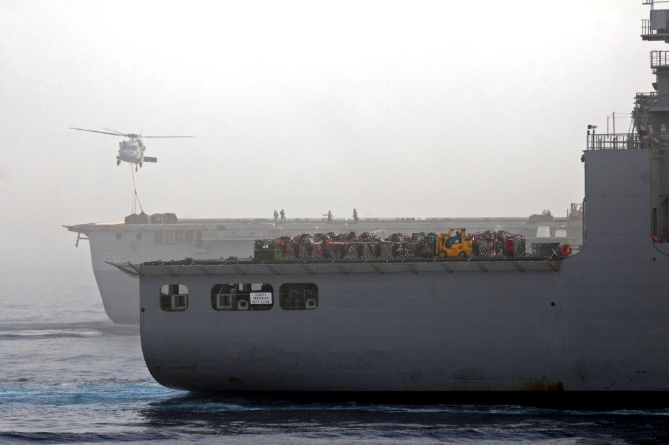 A U.S. Navy MH-60S Knighthawk helicopter assigned to Helicopter Sea Combat Squadron (HSC) 26 moves cargo from amphibious transport dock ship USS Green Bay (LPD 20), background, to Military Sealift Command dry 110717-N-RC734-144