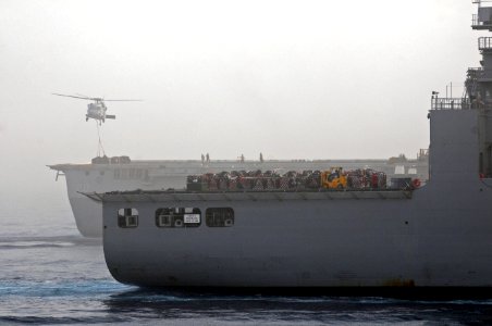 A U.S. Navy MH-60S Knighthawk helicopter assigned to Helicopter Sea Combat Squadron (HSC) 26 moves cargo from amphibious transport dock ship USS Green Bay (LPD 20), background, to Military Sealift Command dry 110717-N-RC734-144