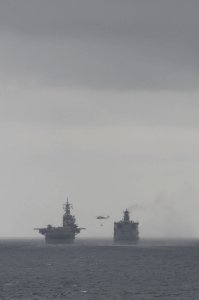 A U.S. Navy MH-60S Seahawk helicopter, assigned to Helicopter Sea Combat Squadron (HSC) 23, transports supplies from the fleet replenishment oiler USNS Rappahannock (T-AO 204) to the amphibious assault ship USS 110316-N-RC734-169