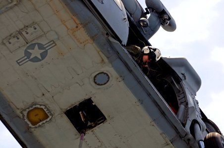 A U.S. Navy naval air crewman checks to see that an MH-60S Seahawk helicopter assigned to Helicopter Sea Combat Squadron (HSC) 23 is clear of the flight deck during a vertical replenishment between Military 110517-N-RC734-314