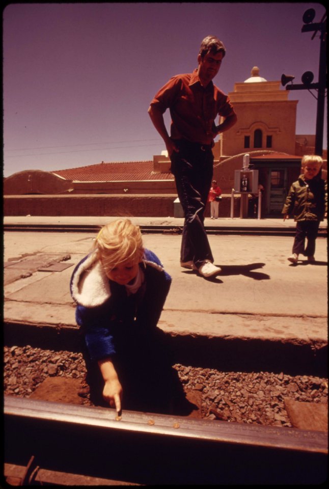A-child-places-pennies-on-the-track-at-the-albuquerque-new-mexico-train-station-and-will-wait-for-the-southwest-limited-to-flatten-them-as-a-souvenir-june-1974 7158191496 o