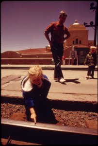 A-child-places-pennies-on-the-track-at-the-albuquerque-new-mexico-train-station-and-will-wait-for-the-southwest-limited-to-flatten-them-as-a-souvenir-june-1974 7158191496 o