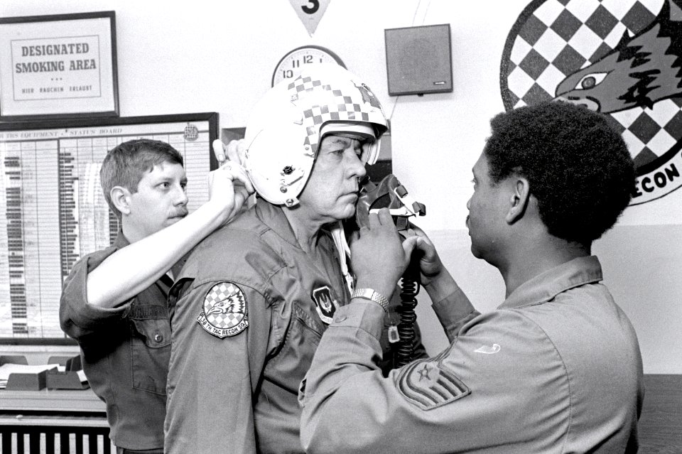 A1C Joseph A. Gallagher, left, and TSGT Kenneth Robinson, right, of the 26th Tactical Reconnaissance Squadron assist Ambassador to Belgium Charles H. Price with his helmet prior to his flight in an F-15D Eagle aircraft DF-SN-82-09027