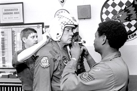 A1C Joseph A. Gallagher, left, and TSGT Kenneth Robinson, right, of the 26th Tactical Reconnaissance Squadron assist Ambassador to Belgium Charles H. Price with his helmet prior to his flight in an F-15D Eagle aircraft DF-SN-82-09027