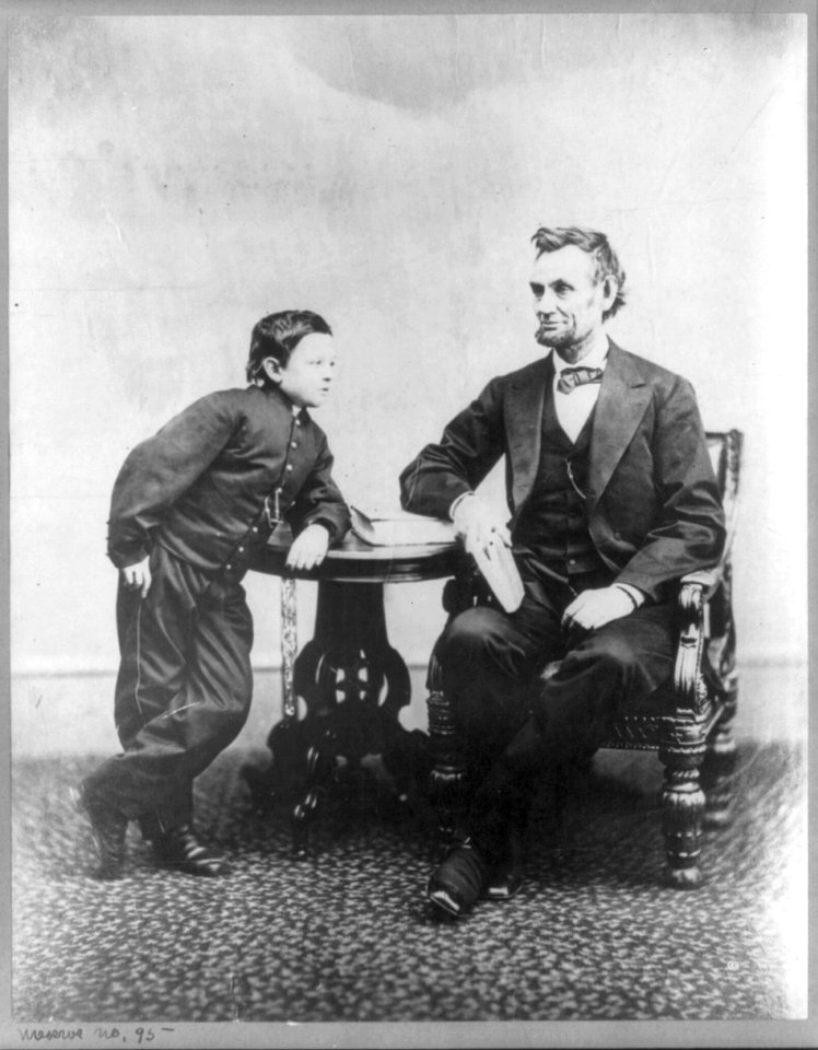Abraham Lincoln, seated and holding a book, with his son Tad (Thomas) leaning on a table LCCN2007675781