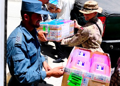 Afghan National Civil Order Police and Coalition Forces load boxes of school supplies onto a truck to distribute them to a nearby school. (4678253932)