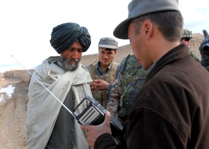 Afghan Police officer hands out radios keyed to RADIO GURESHK in Mayai Village, Gureshk district, Helmand Province, photo