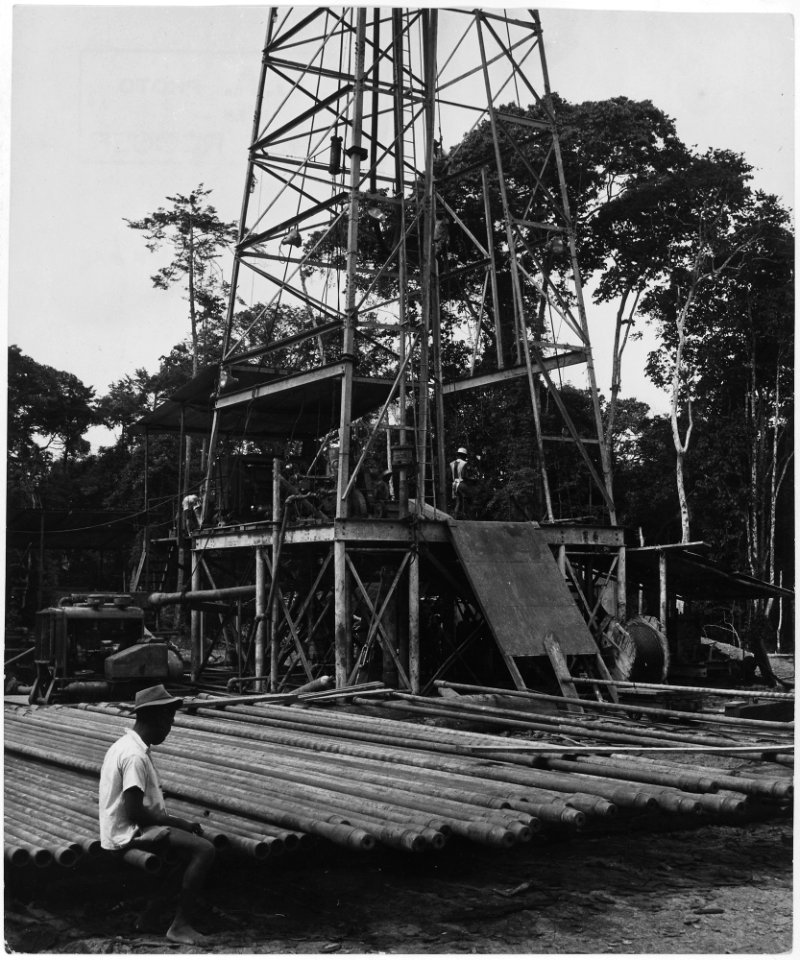 Africa. Gabon, French Equatorial Africa. The rig is up, a native laborer sits sleepily on the scores of drill pipe... - NARA - 541652