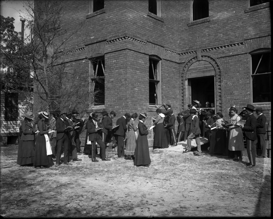 African American men and women students outside a brick building with notebooks at Tuskegee Normal and Industrial Institute, Alabama LCCN2017650161