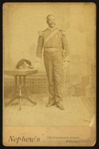 African American soldier, full-length portrait, wearing GAR medal, standing next to table) - Nephew's, 493 Pennsylvania Avenue, Washington, D. C LCCN2010645149