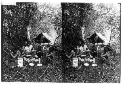 Africans cooking in campsite, deer hanging from tree and an antelope lying by tent LCCN2002706439