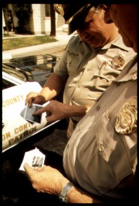 AIR POLLUTION CONTROL DEPARTMENT OFFICERS COMPARING POLAROID PHOTOS TO IDENTIFY VIOLATOR BEFORE - NARA - 542756 photo