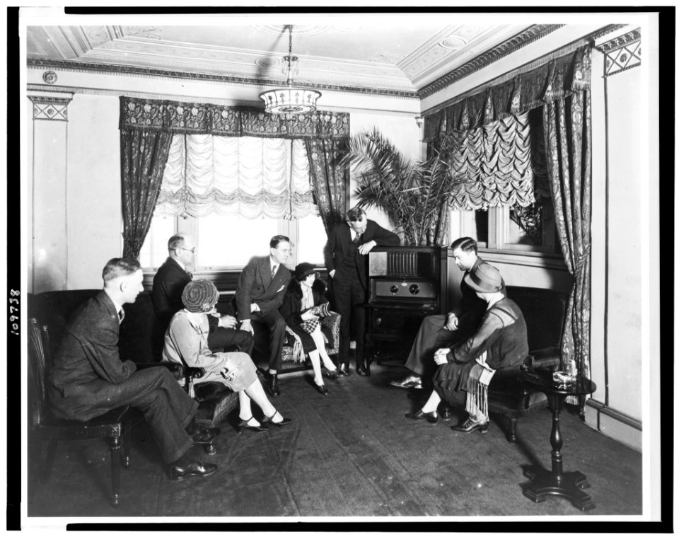 Atwater Kent, standing by radio, and seven other people listening to the radio, in the Hamilton Hotel, Washington, D.C. LCCN94501550