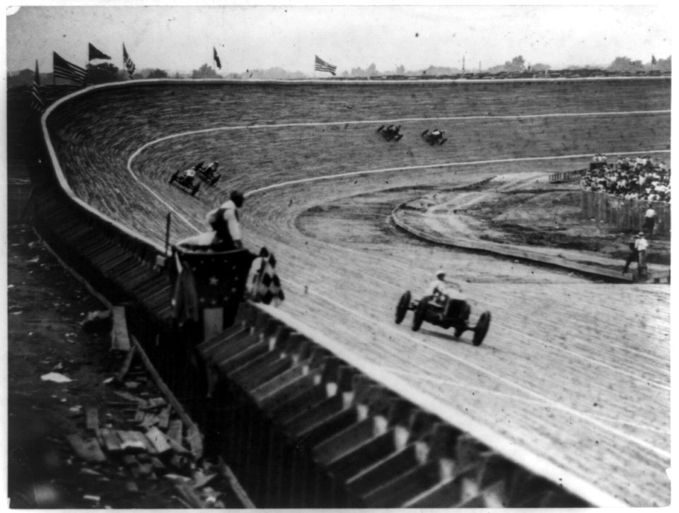 Automobile racing on curved wood track, probably in or near Washington, D.C., with flag man in foreground LCCN89711941