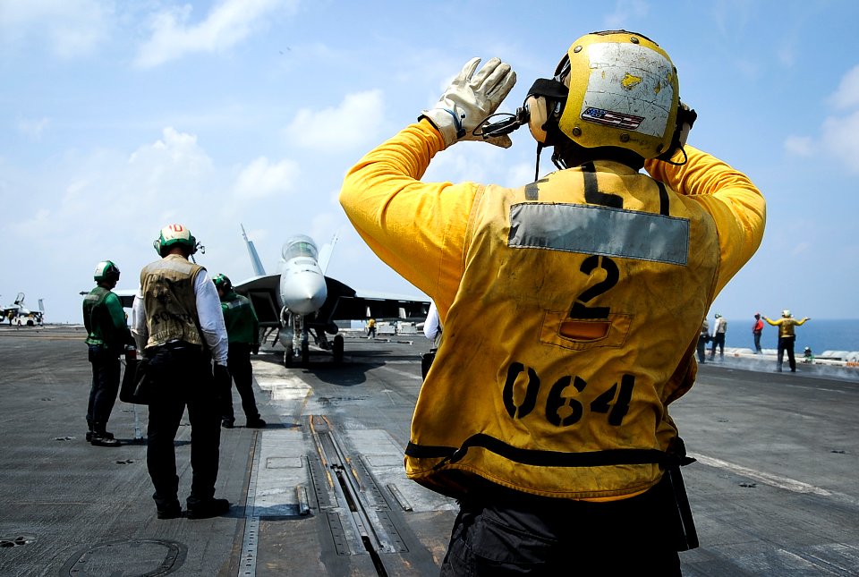 Aviation Boatswain's Mate (Handling) 1st Class Joshue Chinbritton directs an FA-18F Super Hornet onto a catapult on the flight deck of the USS Theodore Roosevelt