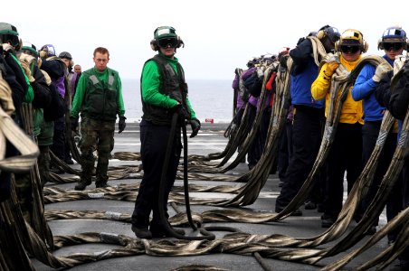 Aviation Boatswain's Mate (Equipment) Airman Alexander Miller, center, prepares to stow a barricade below the flight deck of the aircraft carrier USS Ronald Reagan (CVN 76)