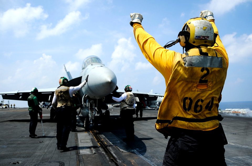 Aviation Boatswain's Mate (Handling) 1st Class Joshue Chinbritton directs an FA-18F Super Hornet onto a catapult on the flight deck of the aircraft carrier USS Theodore Roosevelt
