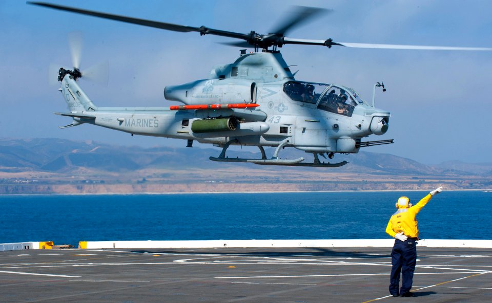 Aviation Boatswain's Mate (Handling) 3rd Class guides a Marine Corps AH-1Z Viper attack helicopter