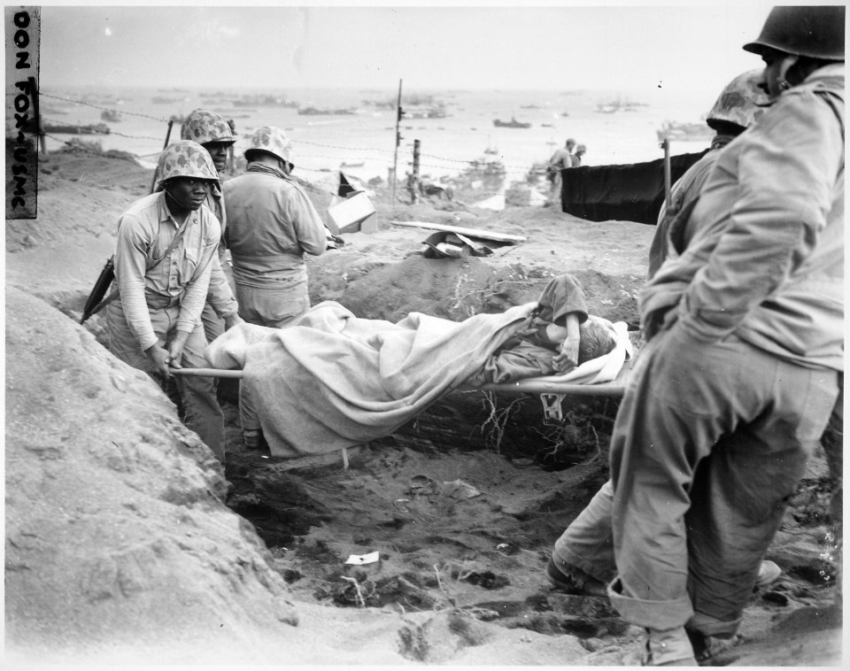 Carrying a Jap(anese) prisoner from stockade to be evacuated and treated for malnutrition. Iwo Jima., 02-23-1945 - NARA - 532544