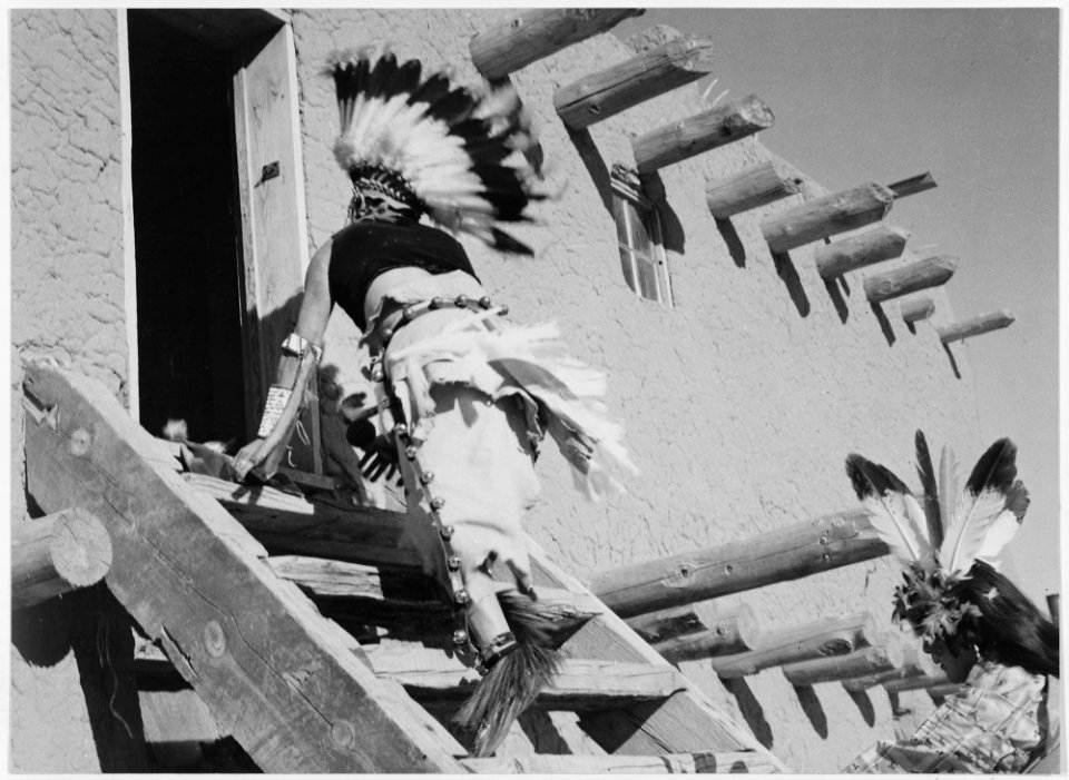 Dance, San Ildefonso Pueblo, New Mexico, 1942, two Indians in headdress ascending stairs to house., 1942 - NARA - 519981