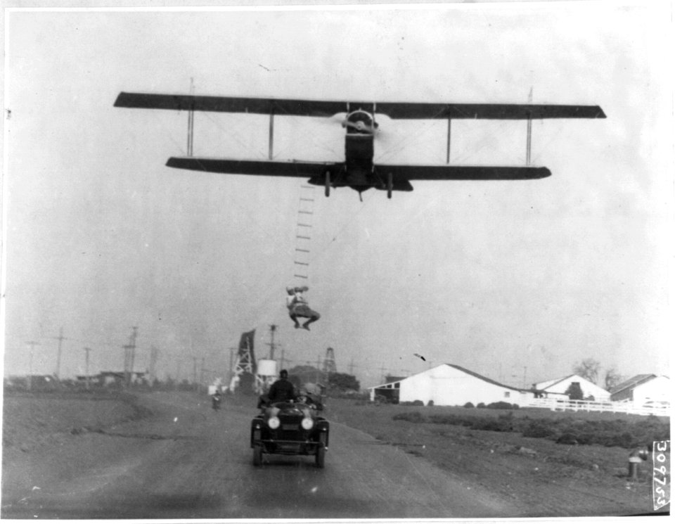 Fearless Freddie, a Hollywood stunt man, clinging to a rope ladder slung from a plane flown by A.M. Maltrup, about to drop into automobile below- automobile shown LCCN2003655445