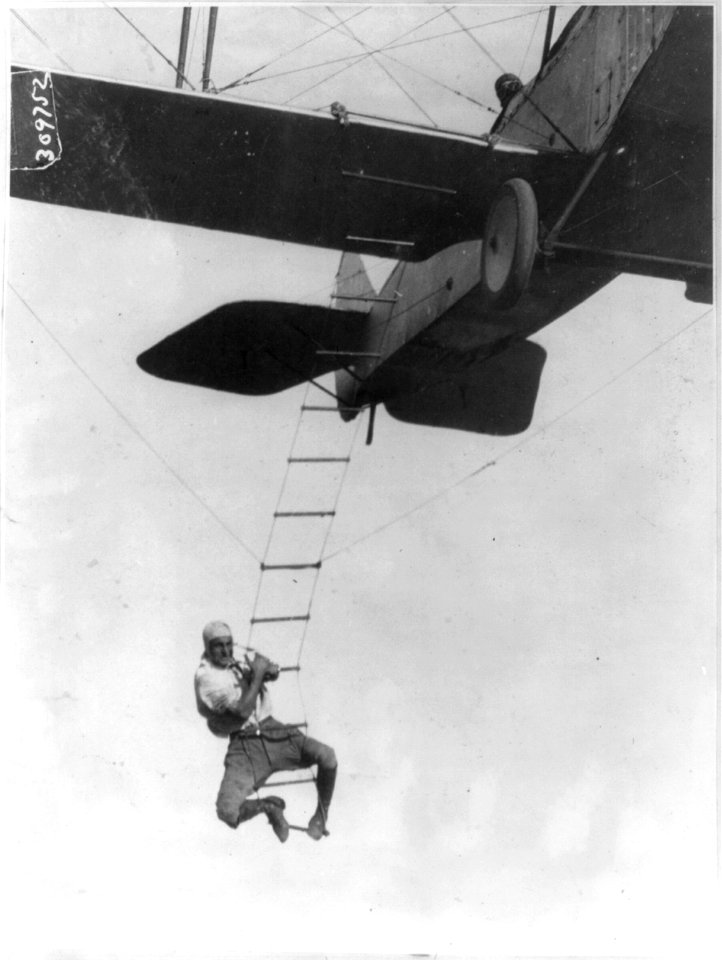 Fearless Freddie, a Hollywood stunt man, clinging to a rope ladder slung from a plane flown by A.M. Maltrup, about to drop into automobile below- automobile not shown LCCN2003655444