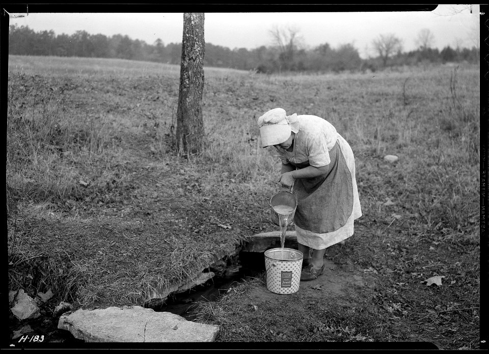 Mrs. Wallace dipping water from spring on farm near Norris townsite recently purchased by the TVA for experimental... - NARA - 532800