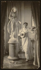 Miss Apperson playing banjo beside statue of Flora in niche of Sen. George Hearst's residence, Washington, D.C. LCCN2001704031