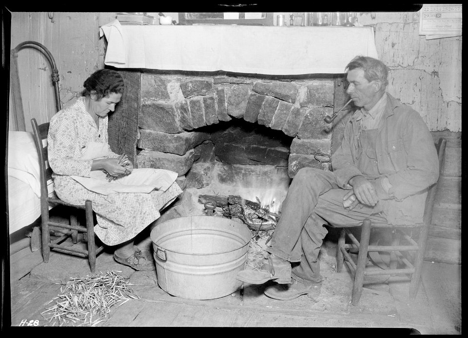 Mr. J. W. Melton and his wife by the fireplace getting ready for supper. Melton has used up the better part of his... - NARA - 532652