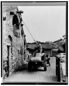 Surprise Valley Farm, Arthur Curtiss James property, Beacon Hill Road, Newport, Rhode Island. Men loading sacks of grain from truck in courtyard into second floor doorway of barn LCCN00651259