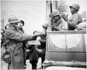 Two smiling French soldiers fill the hands of American soldiers with candy, in Rouffach, France, after the closing of t - NARA - 531247