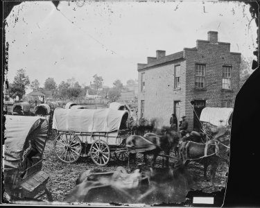 (View of a brick building, and wagons with teams of horses.) - NARA - 528100 photo