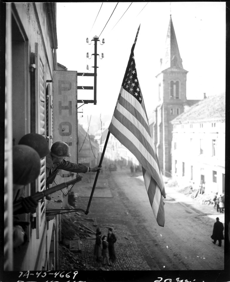 111-SC-202712 - Capt. Thomas H. Garahan, Brooklyn, New York, raises American flag as Bitche, France, falls to the 100th Infantry Division, US Seventh Army, after a siege of many months. He was with the first troops to enter the town