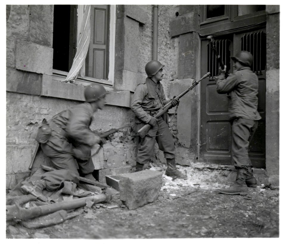 111-SC-197564-S - Three Americans of the 117th Infantry Regiment are about to enter a house where several enemy snipers are holding out. The town where this action took place, is Stavelot, Belgium