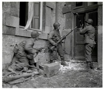 111-SC-197564-S - Three Americans of the 117th Infantry Regiment are about to enter a house where several enemy snipers are holding out. The town where this action took place, is Stavelot, Belgium