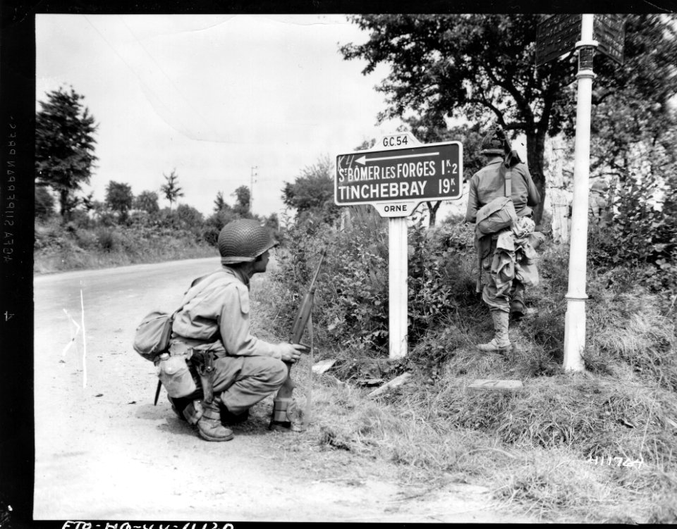 111-SC-411764 - Infantrymen of Company B, 120th Infantry Regiment, 30th Division, cut through a field alongside a road to avoid crossing in the open and giving German snipers a target