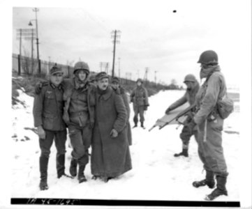 111-SC-326033 - German prisoners taken in drive south of Colmar carry a wounded American with them as they are marched out of the battle area. 4 February, 1945 photo