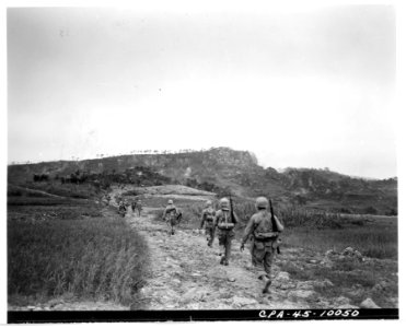 111-SC-337968 - A patrol of the 381st Inf., 96th Div. advance against Big Apple hill which is visible in the background. 10 June 1945 photo